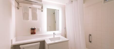 A bathroom with a toilet, sink, and shower area.