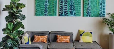 A modern living room with a grey sofa, wooden coffee table, and hanging wicker pendant lights.