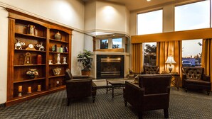 A hotel lobby with a fireplace, seating area, and a large bookshelf. - Baymont by Wyndham Bellingham (Bellingham)