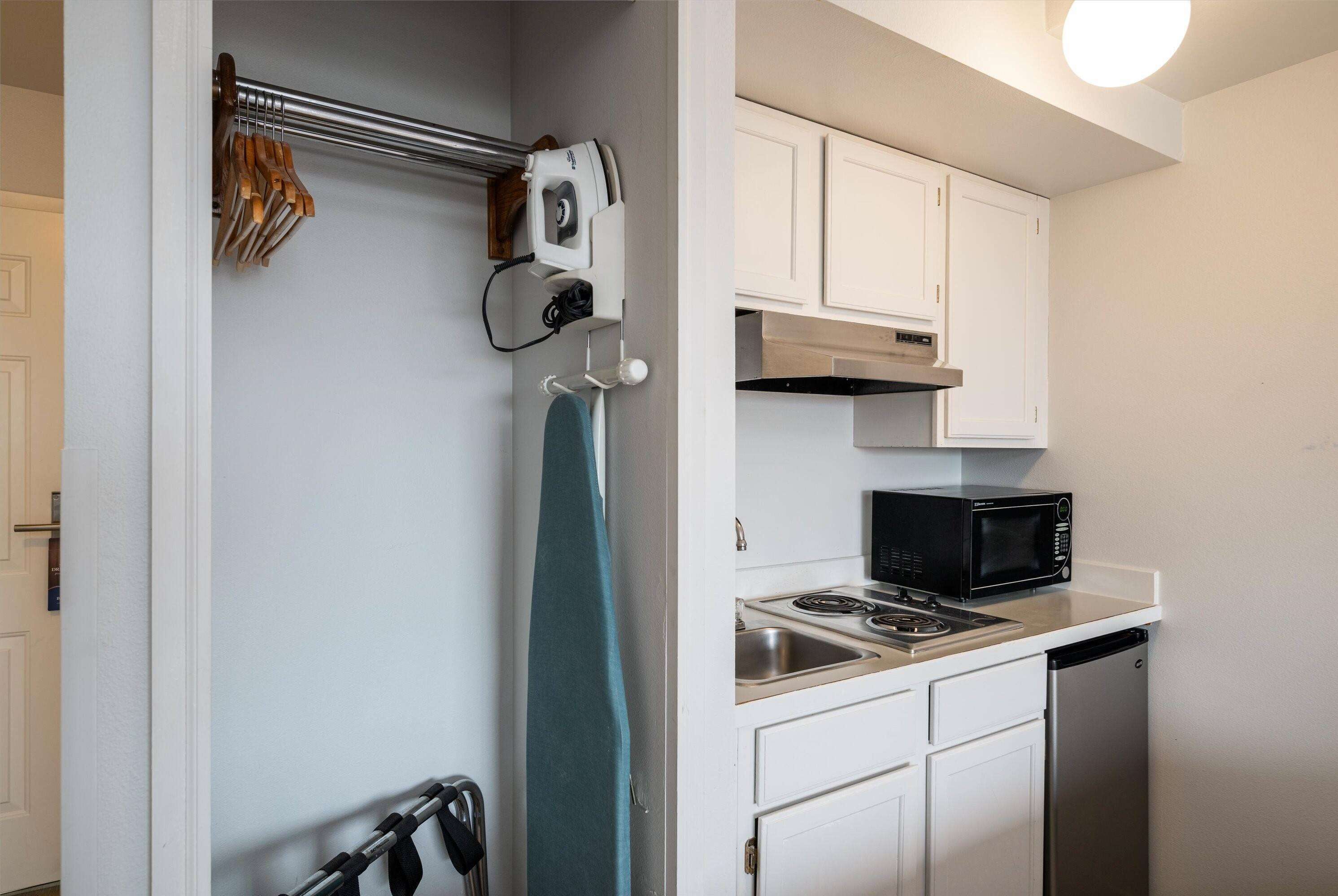 A compact kitchen with white cabinets, a microwave, a stove, and a dishwasher.