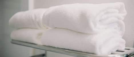 A stack of white towels on a metal towel rack in a bathroom.