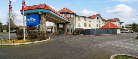A Baymont Inn & Suites with a stone facade, red-tiled roofs, and a parking lot.
