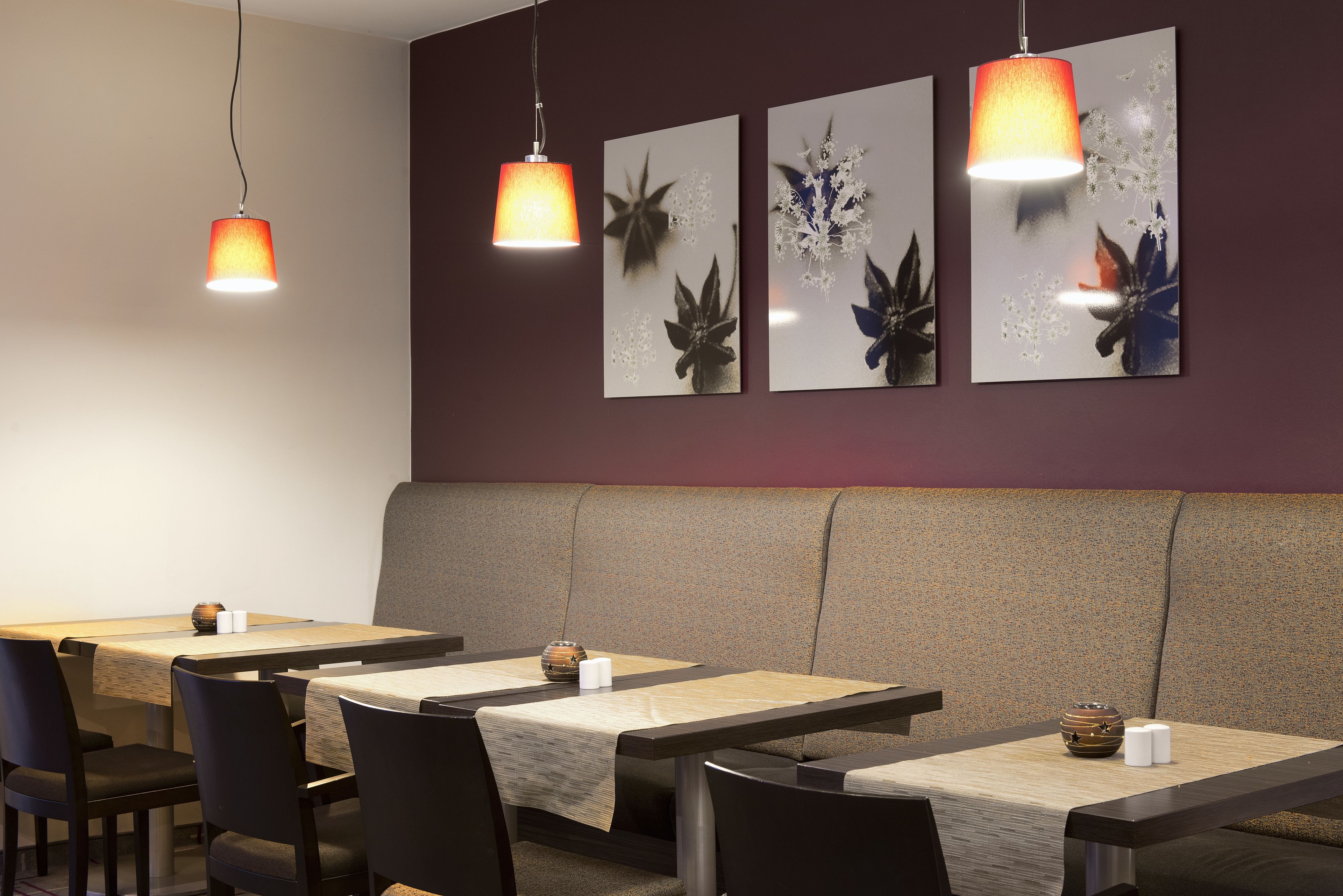 A restaurant interior with tables, chairs, and hanging pendant lights.