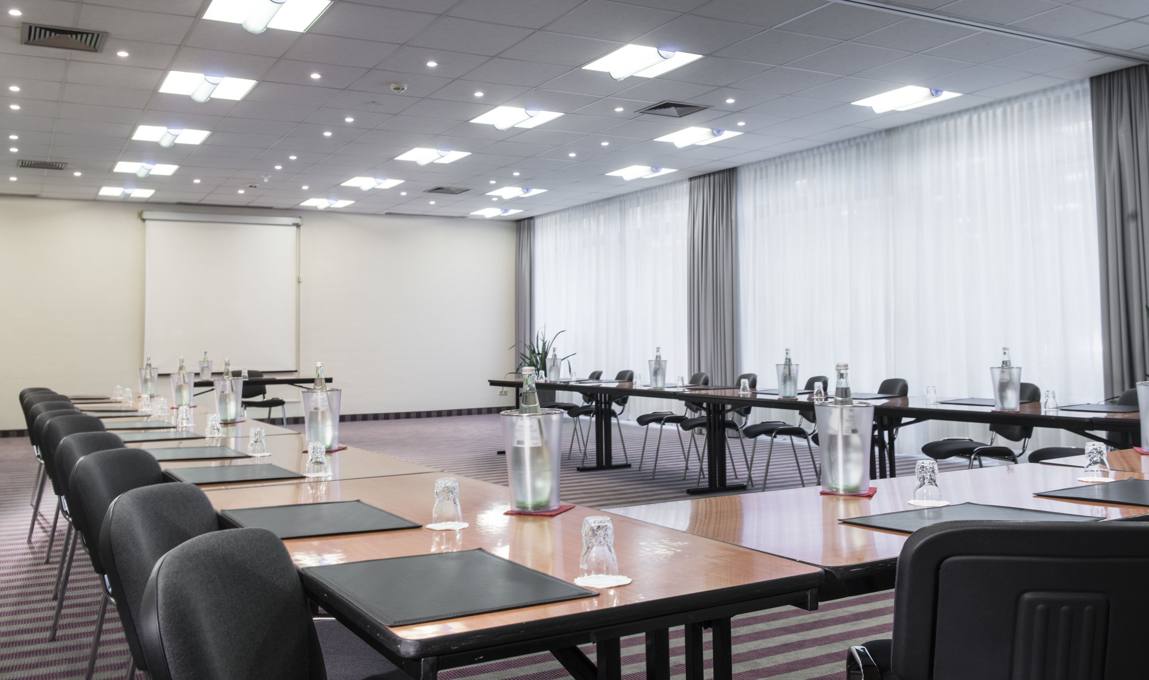 A conference room with multiple tables, chairs, and water bottles.