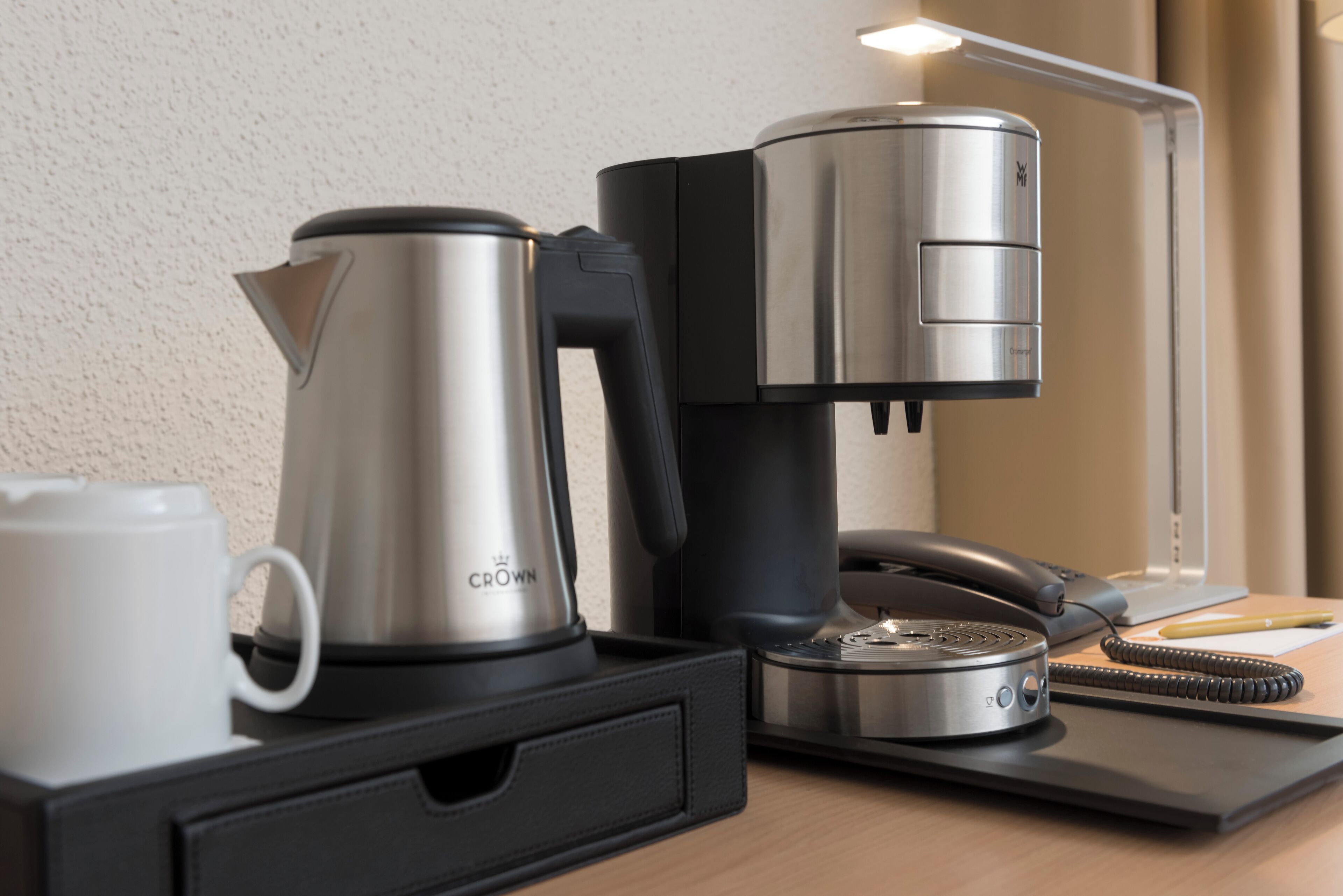 Une machine à café, un téléphone et une tasse sur un bureau.
