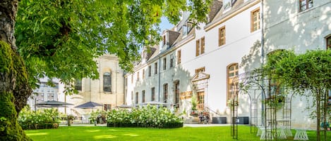 A courtyard with a lawn, a reception area, and a building with multiple windows and a door.