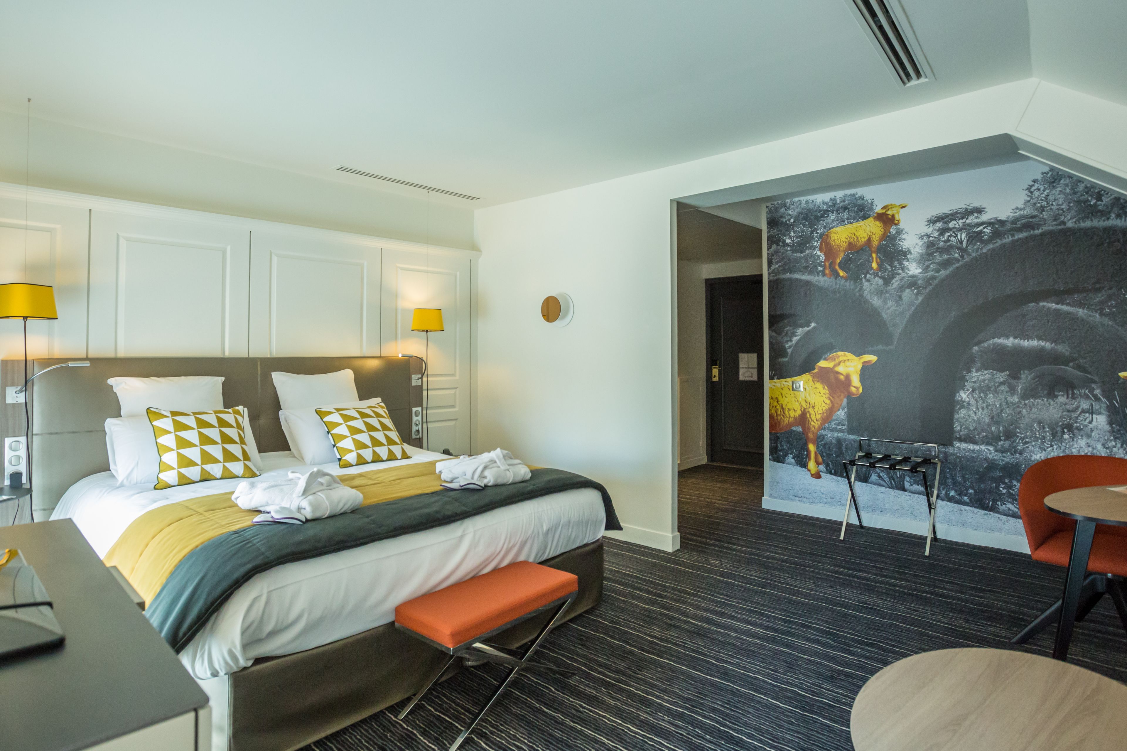 A hotel room with a bed, two bedside lamps, a desk, and a chair.