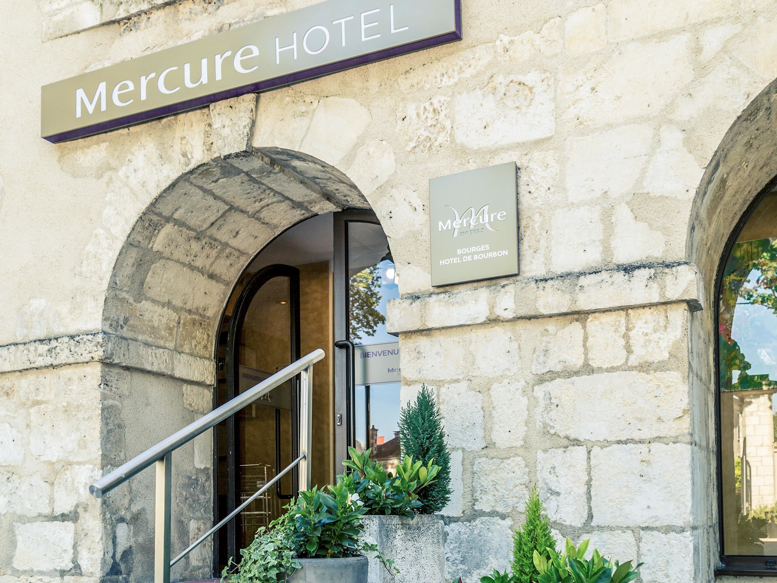 Exterior del Hotel Mercure, con paredes de piedra, un cartel y una escalera.