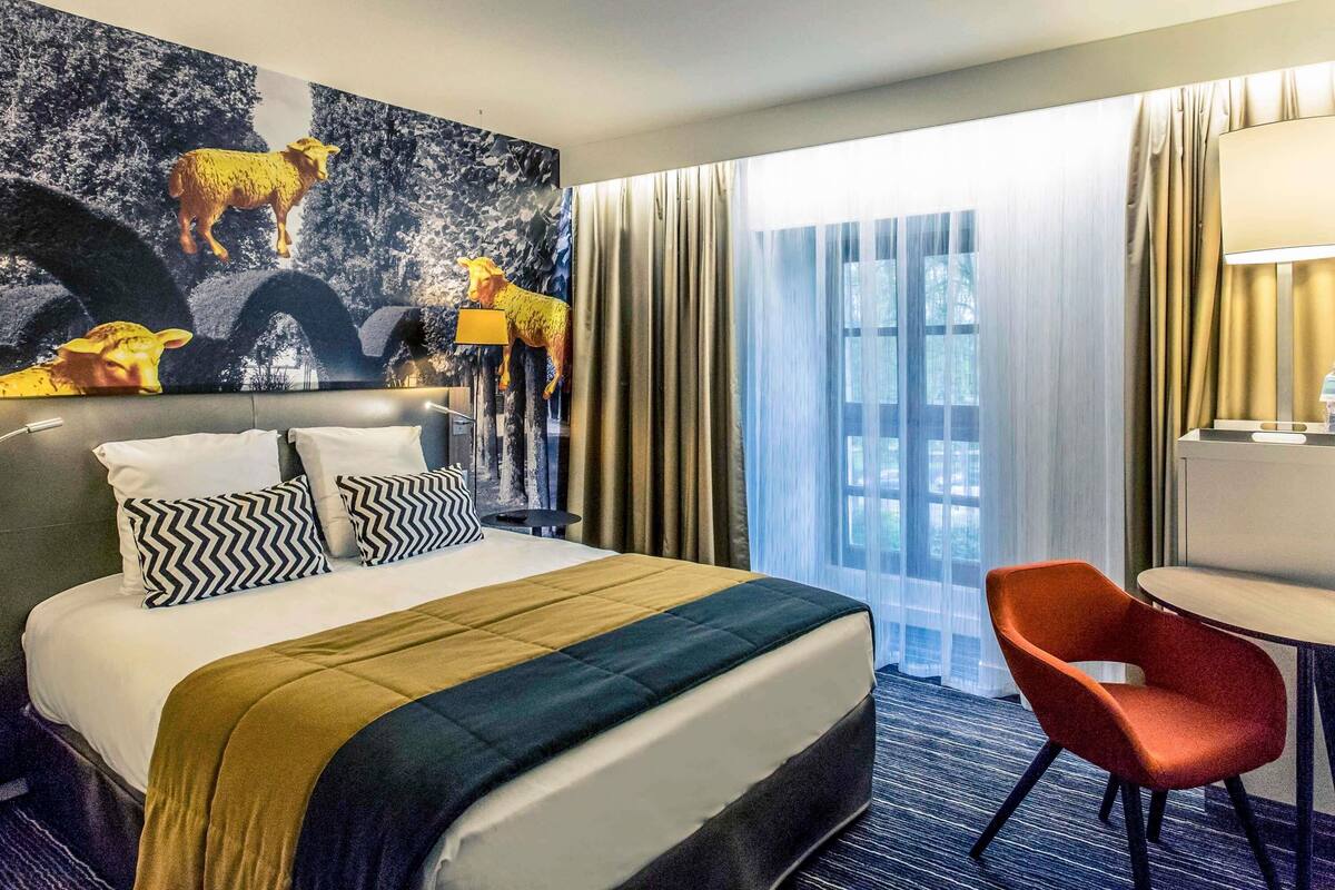 Ein Hotelzimmer mit einem großen Bett, einem Schreibtisch und einem Stuhl.