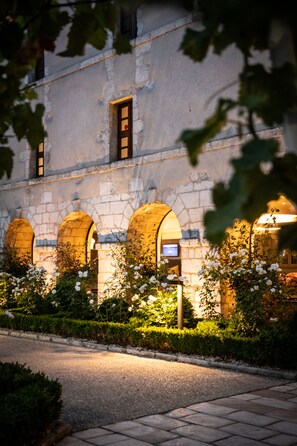 Ein Gebäude aus Stein mit Bogenfenstern und einem Garten mit weißen Blüten.