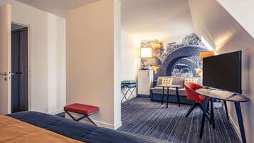 Una habitación de hotel con cama, escritorio, silla, sofá y televisor.