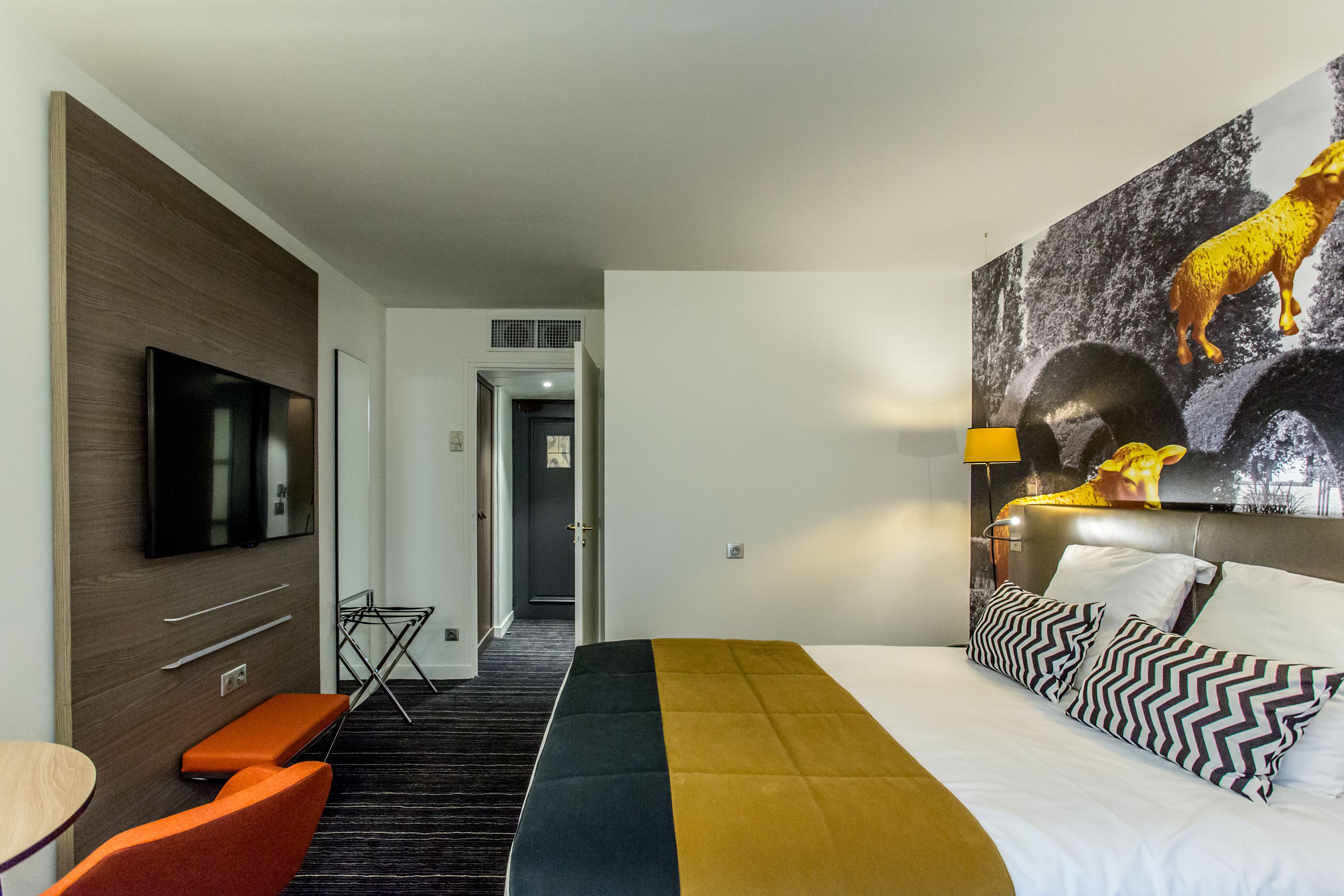 A hotel room with a bed, a TV, a desk, and a chair.