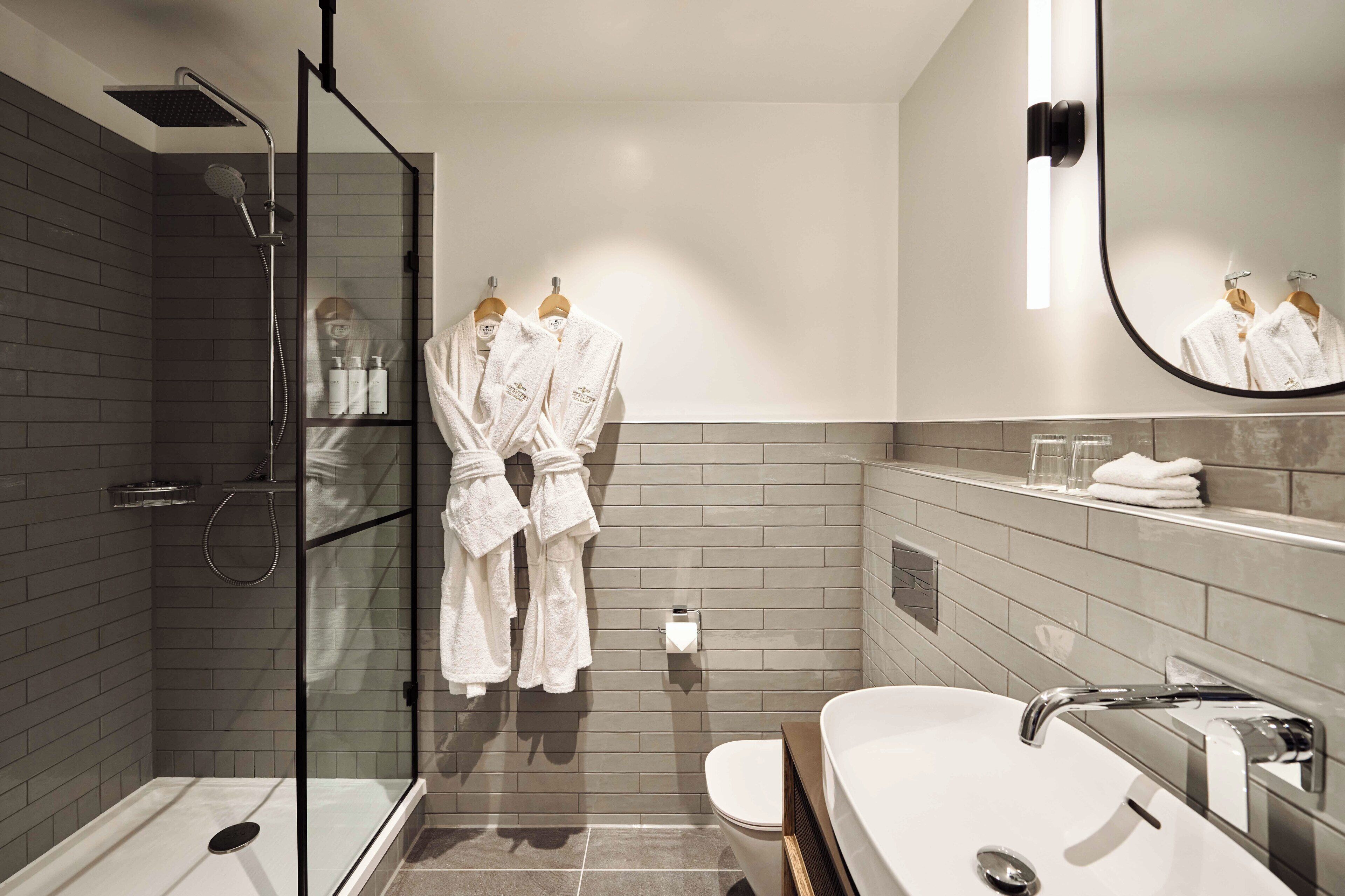 A modern bathroom with a glass-enclosed shower, a white sink, and a large mirror.