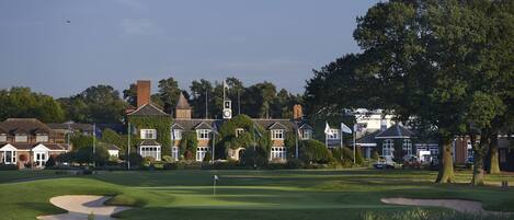 A golf course with a flagstick, sand bunkers, and a pond.