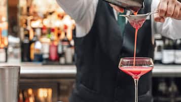 A bartender pouring a drink into a martini glass.