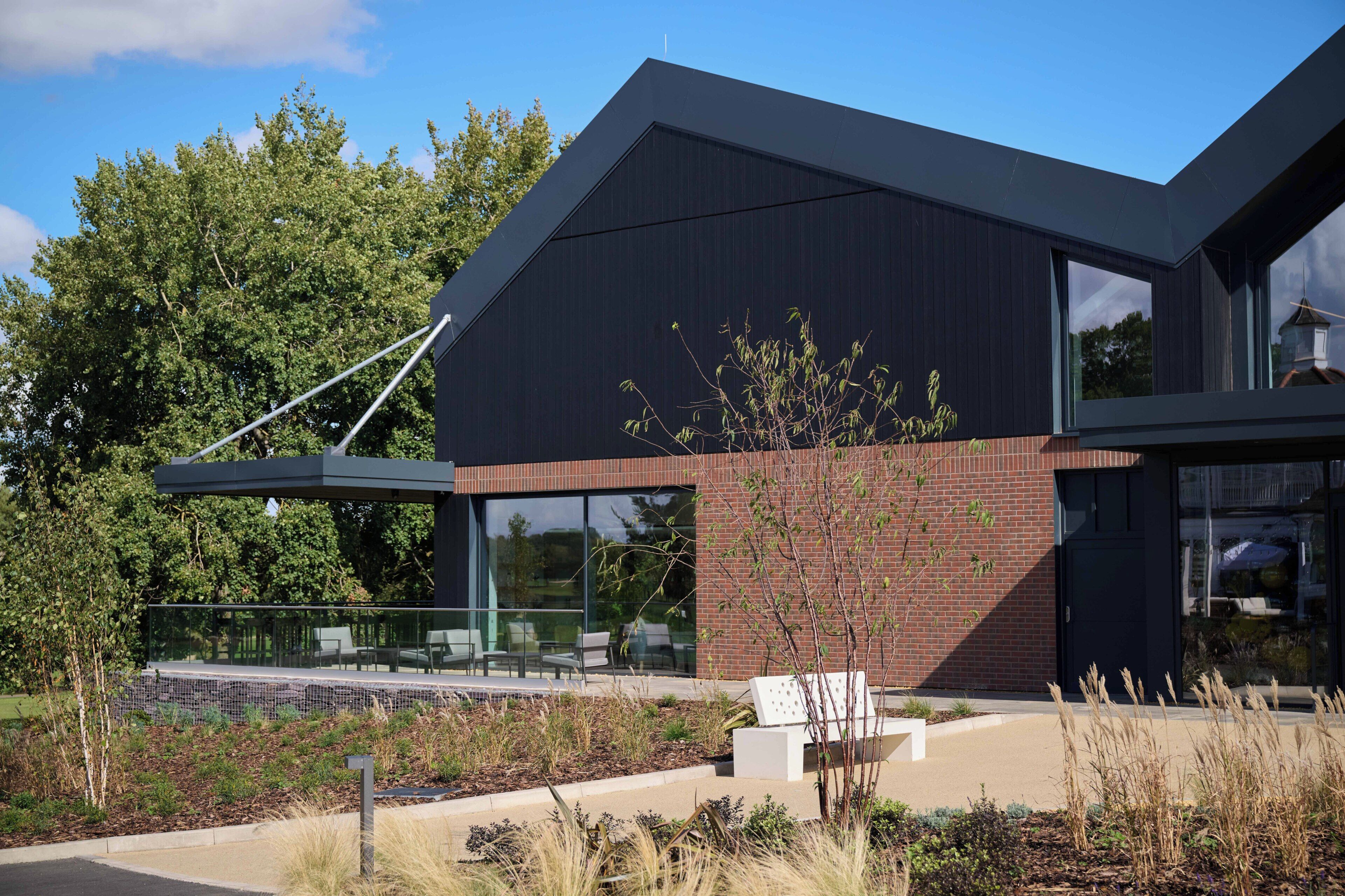 A modern building with a sloped roof, large windows, and a glass balcony.