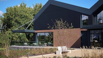 A modern building with a sloped roof, large windows, and a glass balcony.