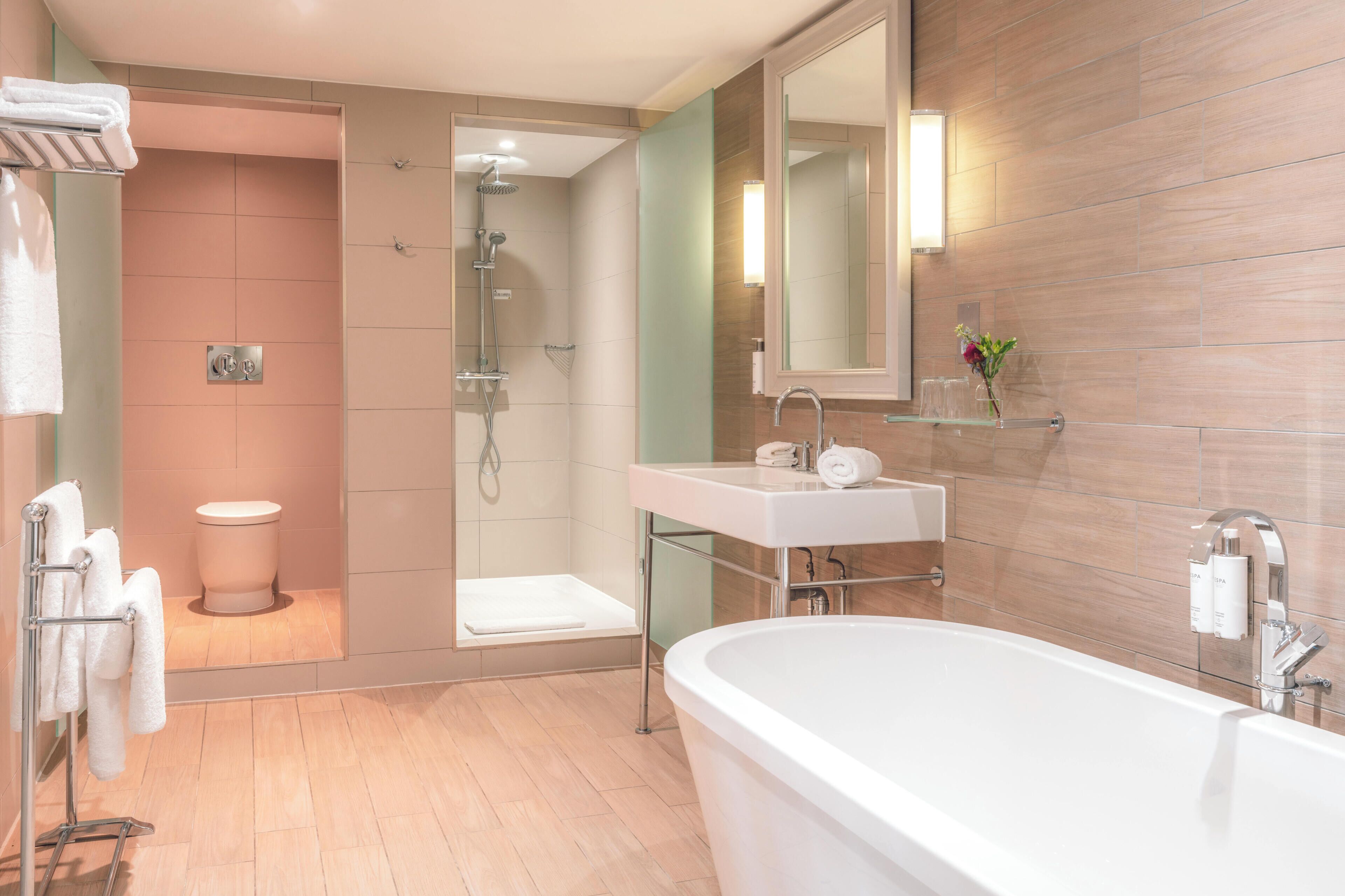 A modern bathroom with a bathtub, shower, toilet, and sink.