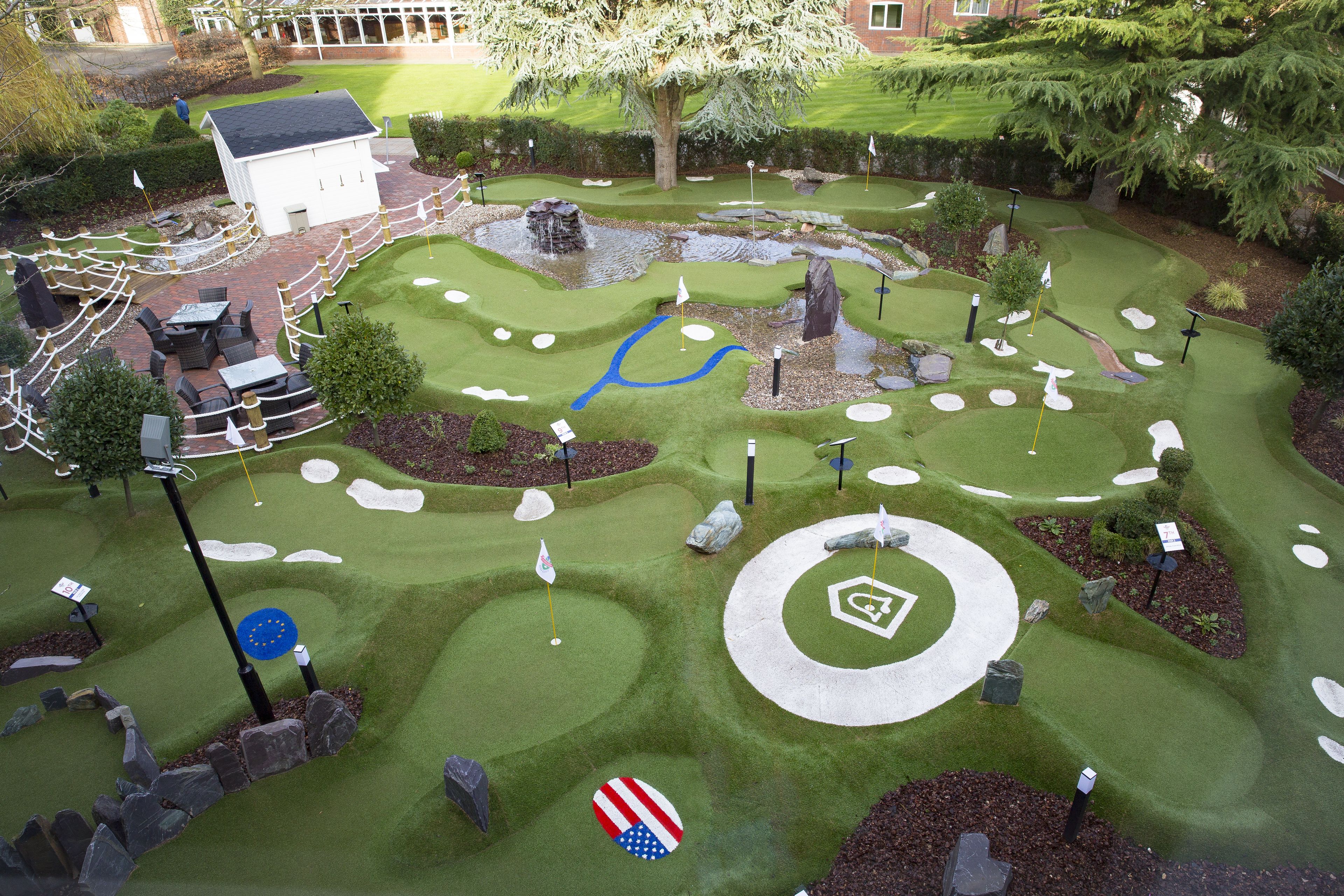 A miniature golf course with a white clubhouse, various holes, and surrounding landscaping.