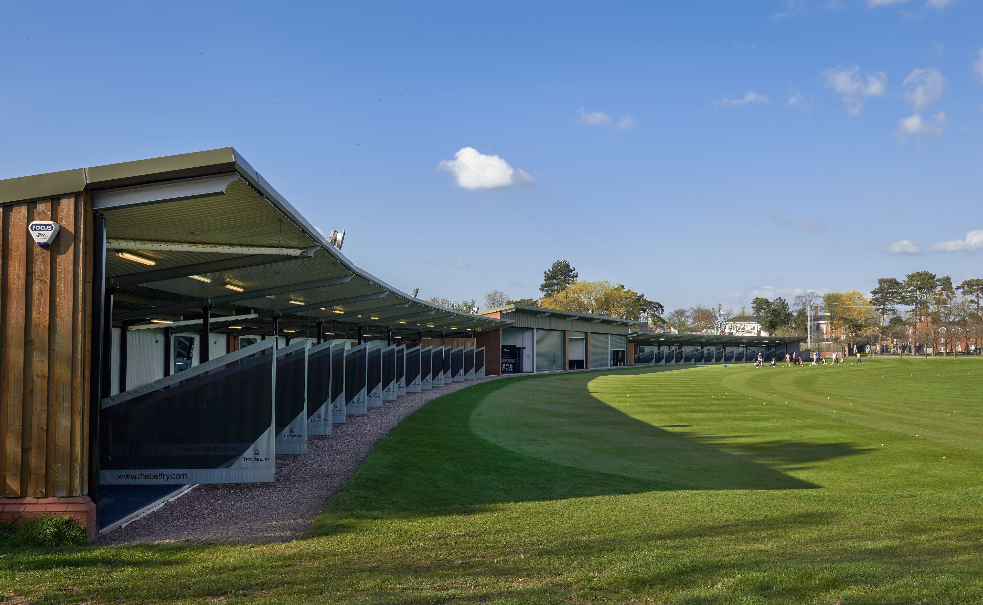 Un complexe sportif moderne doté d’une tribune couverte et d’un terrain en gazon bien entretenu.