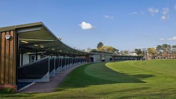 Un complexe sportif moderne doté d’une tribune couverte et d’un terrain en gazon bien entretenu.