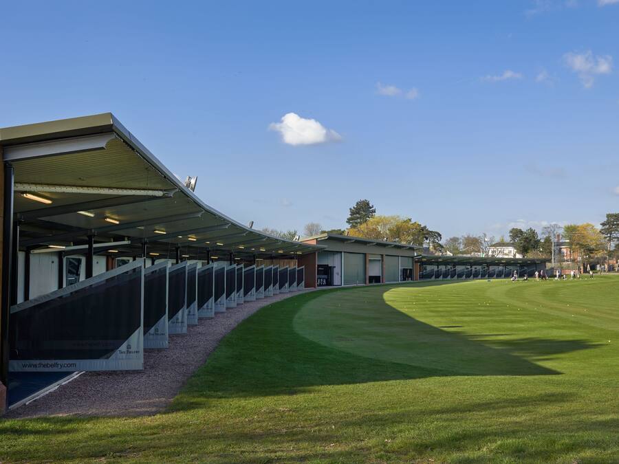 Una instalación deportiva moderna con zona de asientos techada y un césped bien cuidado.