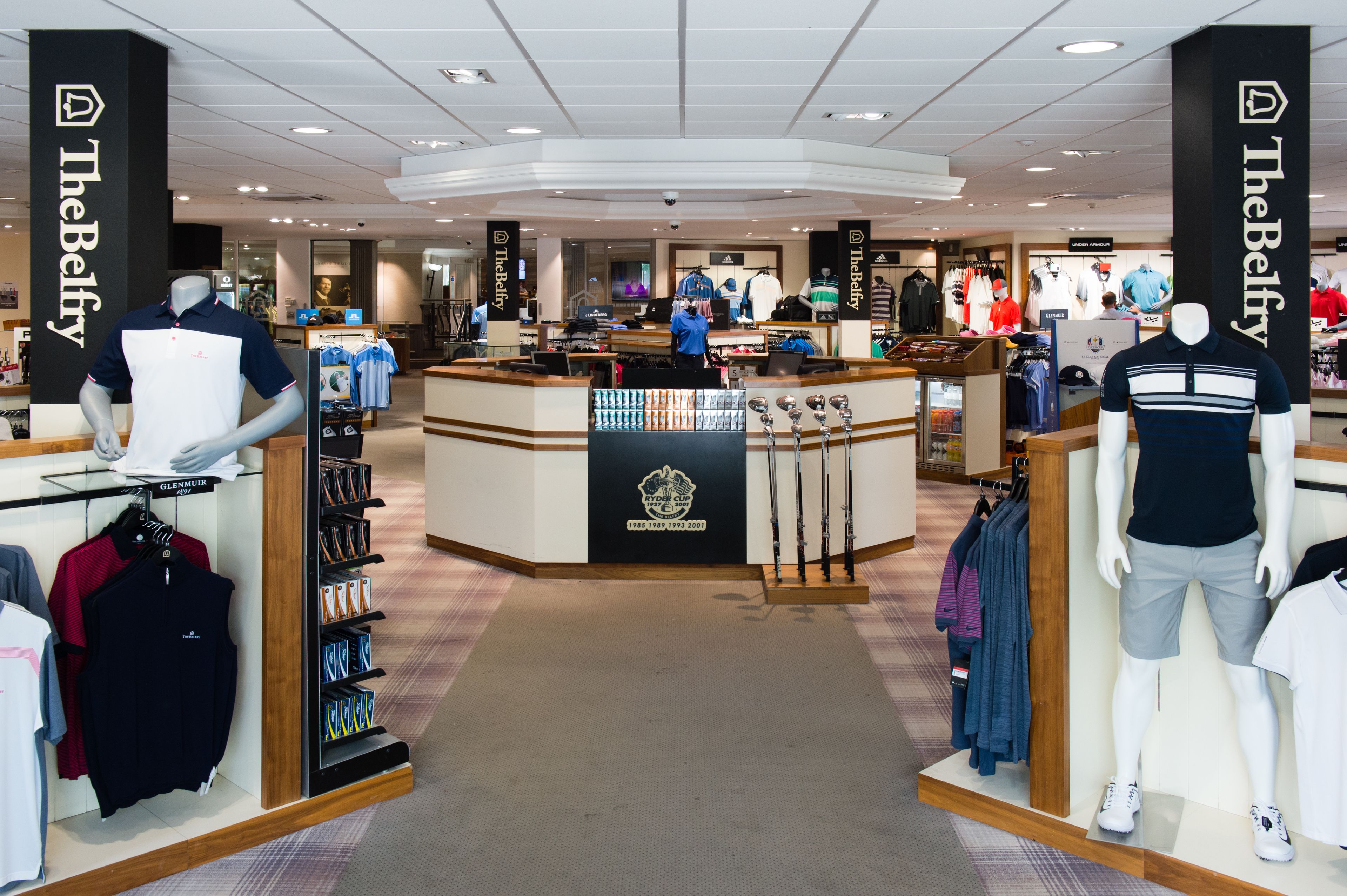 Interior d'una botiga comercial amb maniquís mostrant roba, prestatges amb diversos productes i un taulell central.