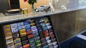 A hotel reception desk with a display of travel guides and a vase of flowers. - Riverside Inn & Suites (Riverside)