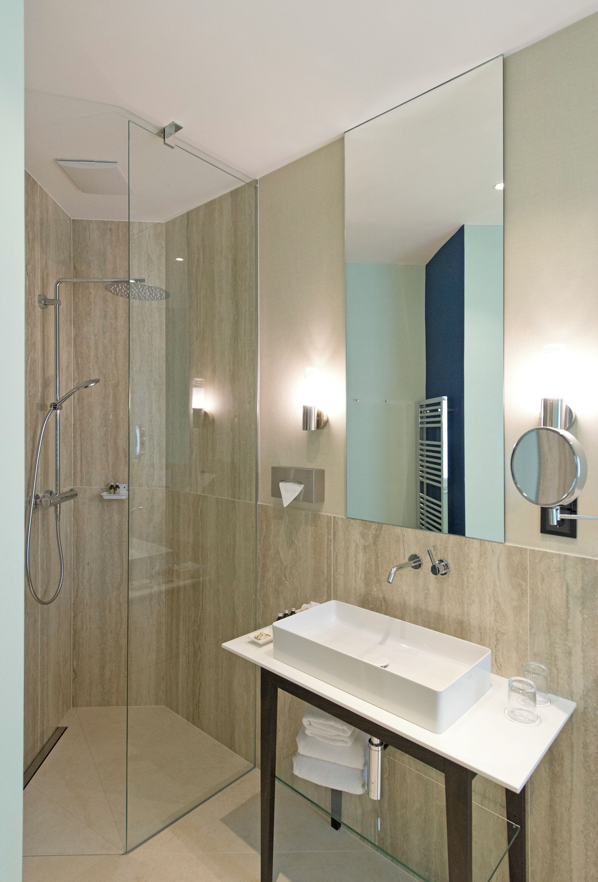Une salle de bain moderne avec une douche à parois de verre, un lavabo blanc et un grand miroir.