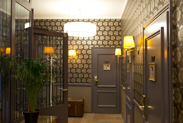 Classic hotel hallway with floral wallpaper, wood floors, and comfortable accommodations.