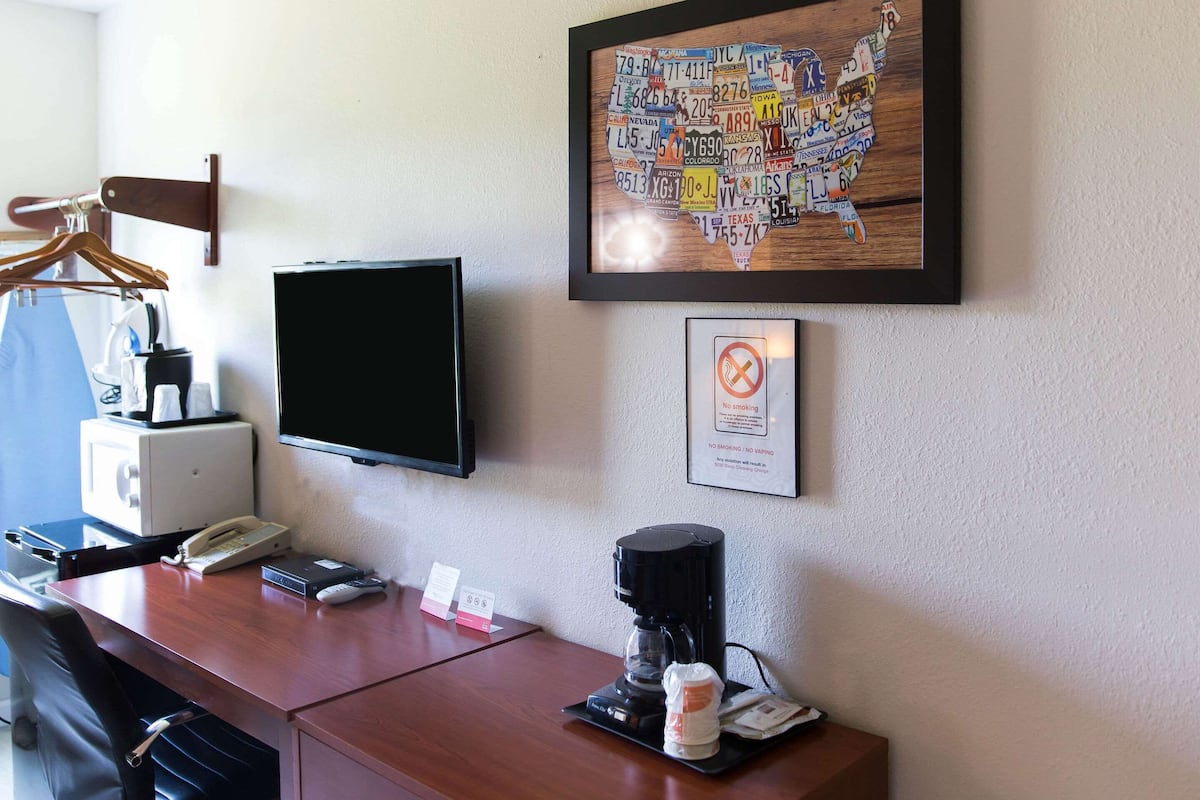 A hotel room with a desk, a television, a coffee maker, and a wall-mounted map of the United States.