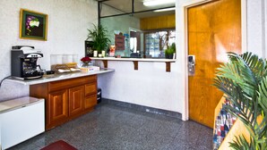 Une petite cuisine équipée d’une machine à café, d’un réfrigérateur et d’un évier. On y trouve un meuble en bois et une plante en pot près de l’évier.