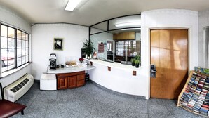 Une chambre d’hôtel compacte dotée d’une kitchenette, d’une porte en bois, d’une fenêtre avec vue et d’un petit coin salon.