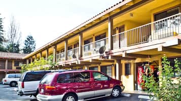 Un motel à la façade jaune, doté de nombreux balcons, avec une voiture rouge garée au premier plan.