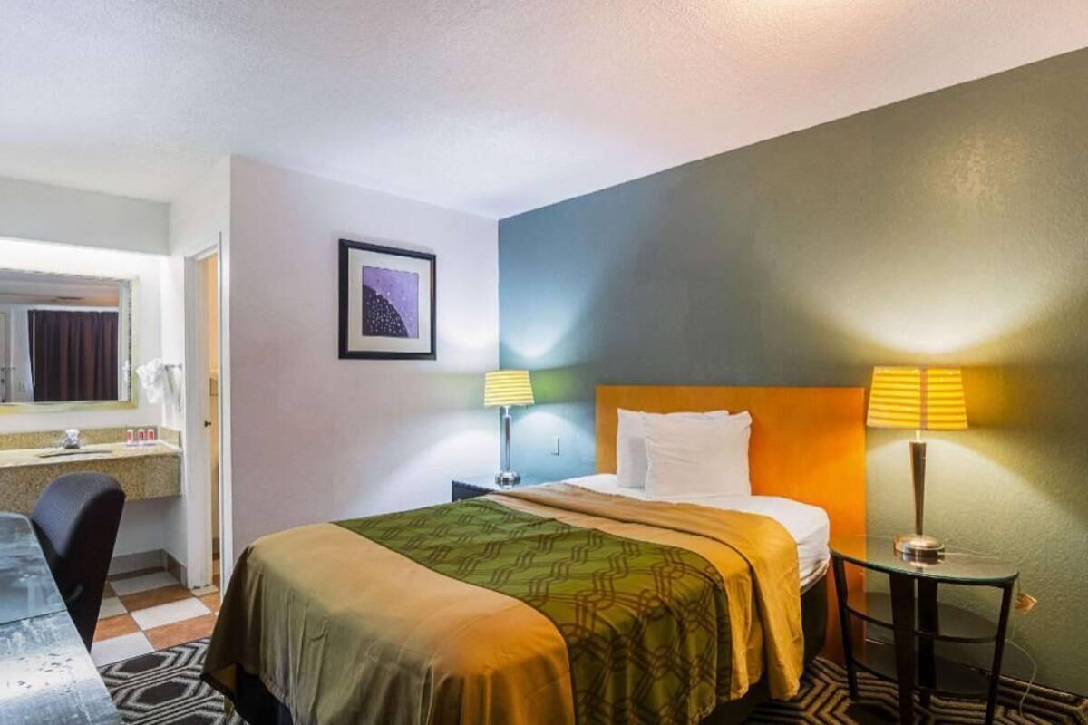 Een hotelkamer met een bed, bedlampen, een bureau en een stoel.