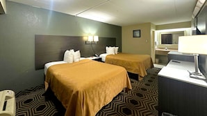 A hotel room with two beds, a desk, a chair, a lamp, and a bathroom visible in the background. - Econo Lodge South Holland - Chicago Southland (South Holland)