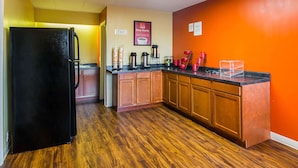 A kitchen with wooden cabinets, a black refrigerator, and a countertop with various appliances. - Econo Lodge South Holland - Chicago Southland (South Holland)