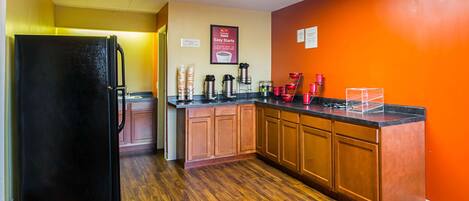 A kitchen with wooden cabinets, a black refrigerator, and a countertop with various appliances.