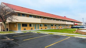 A motel with a red roof, beige exterior, and a parking lot. - Econo Lodge South Holland - Chicago Southland (South Holland)