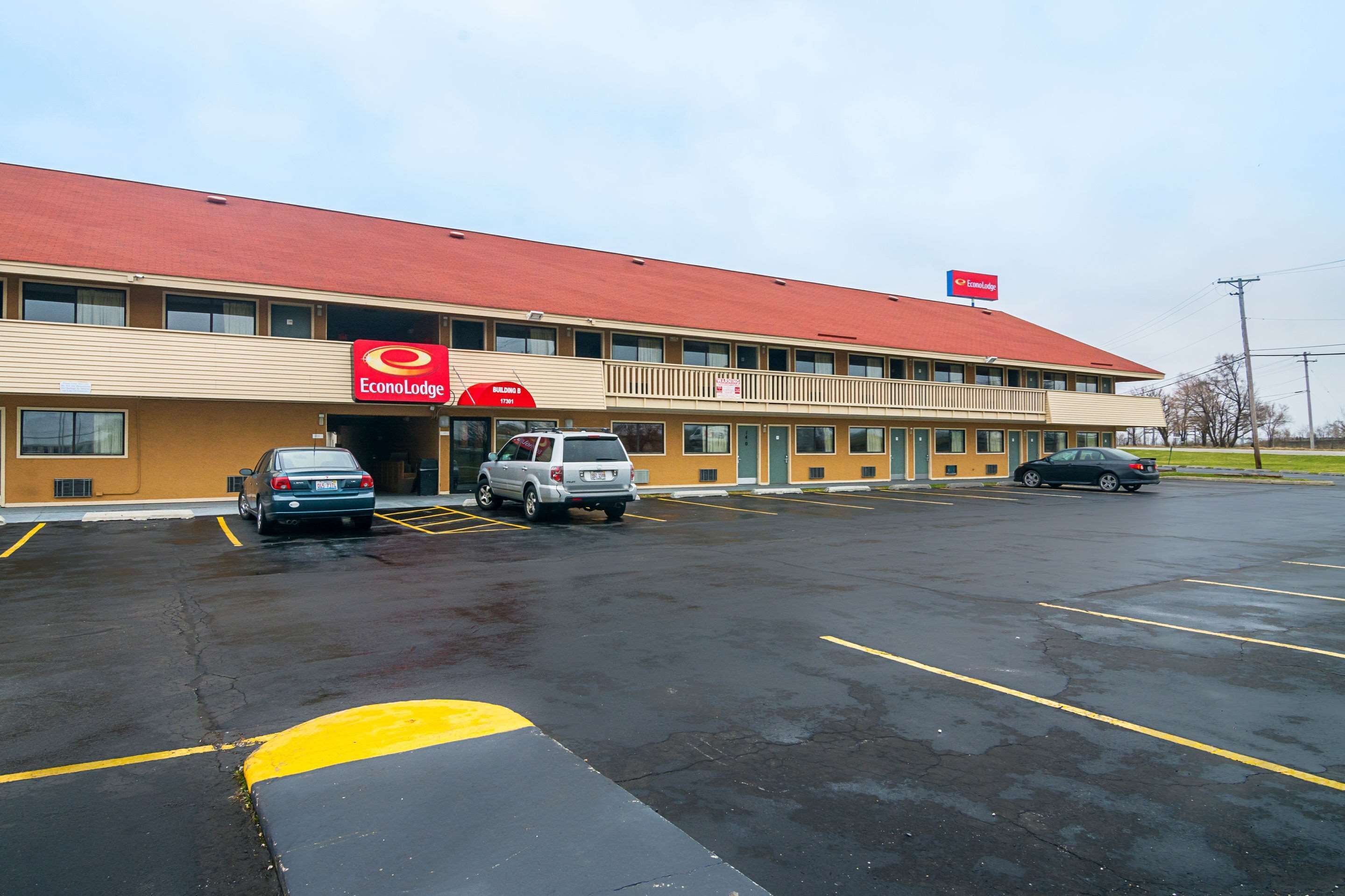 A building with a red roof and a sign for 'EconoLodge'. There are three cars parked in front.