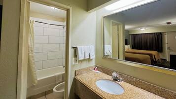 Un baño con bañera, inodoro, lavabo y un espejo grande.