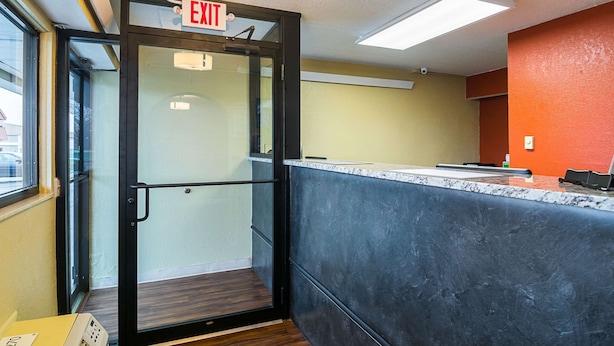 An exit door with a sign, a reception desk, and a view of the outside. - Econo Lodge South Holland - Chicago Southland (South Holland)