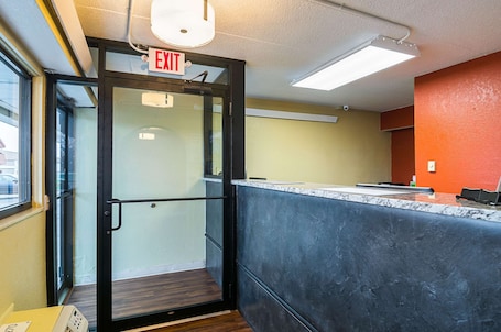 An exit door with a sign, a reception desk, and a view of the outside.