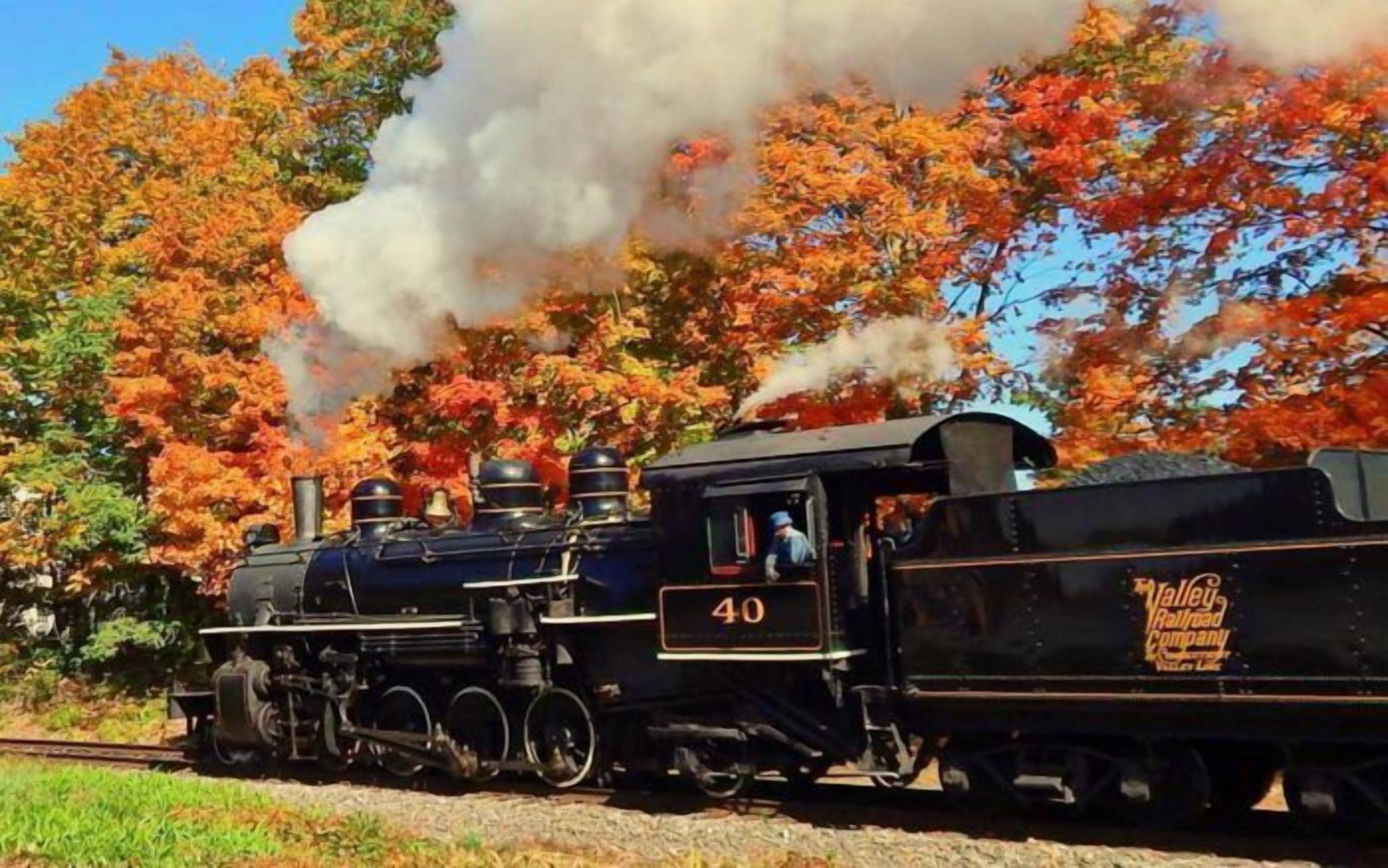 A steam locomotive numbered 40 on a railway track surrounded by autumn foliage.