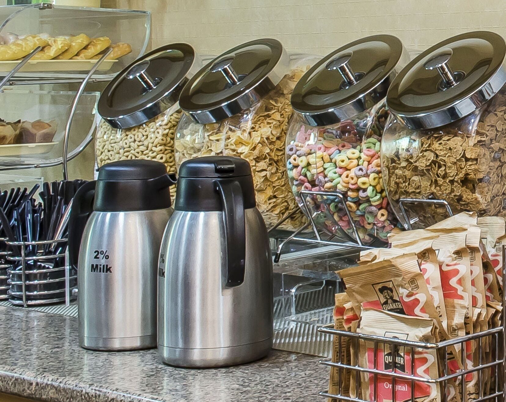 Un'area self-service con distributori per latte e cereali, un contenitore di cereali e una confezione di Quaker Oats.