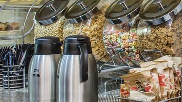 Un'area self-service con distributori per latte e cereali, un contenitore di cereali e una confezione di Quaker Oats.