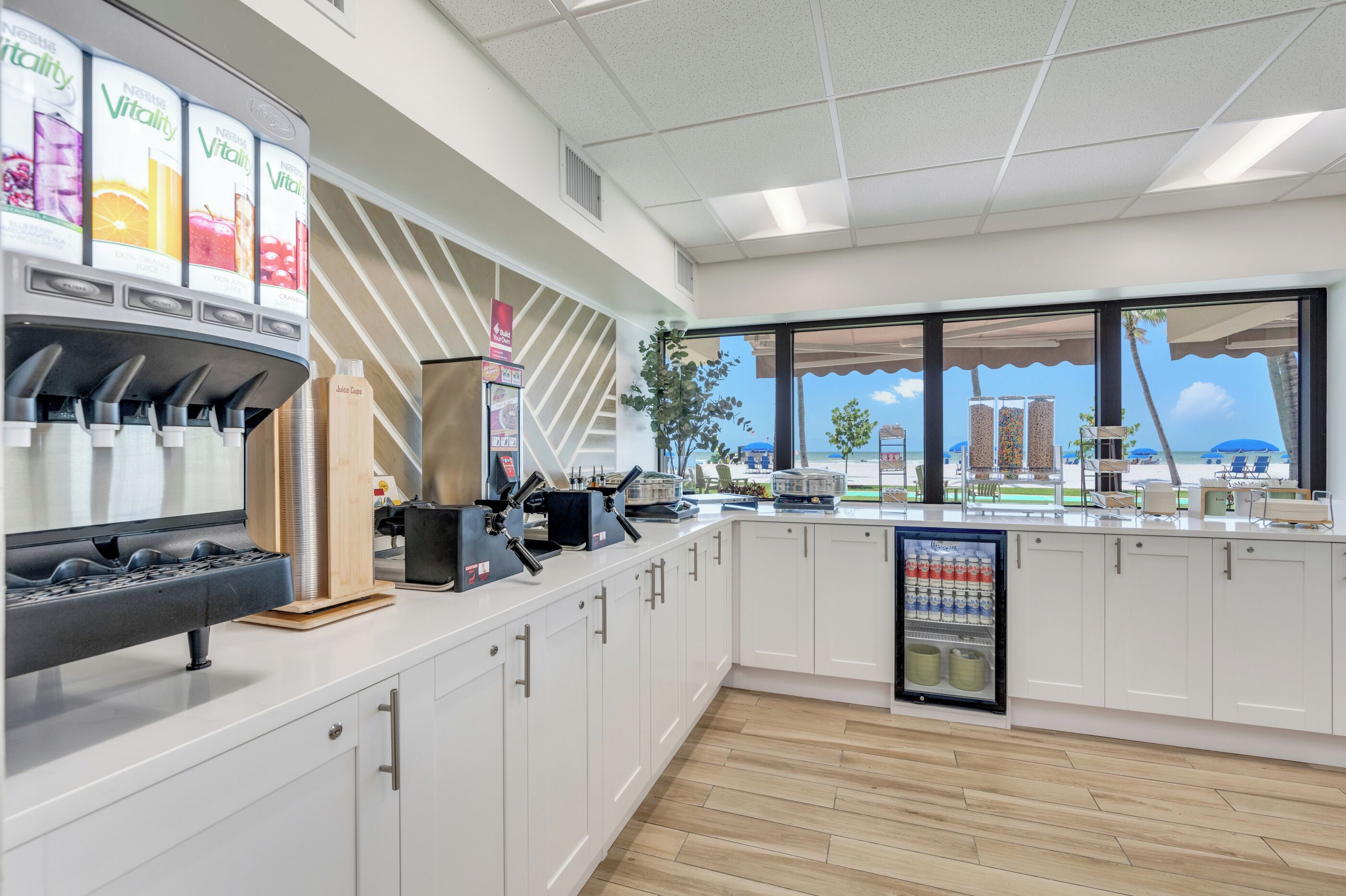 Una cocina moderna con dispensador de zumo, máquina de café y refrigerador.