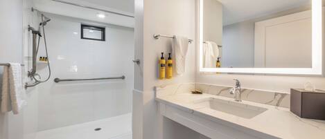 A modern bathroom with a glass-enclosed shower, a white vanity with a large mirror, and a marble countertop.