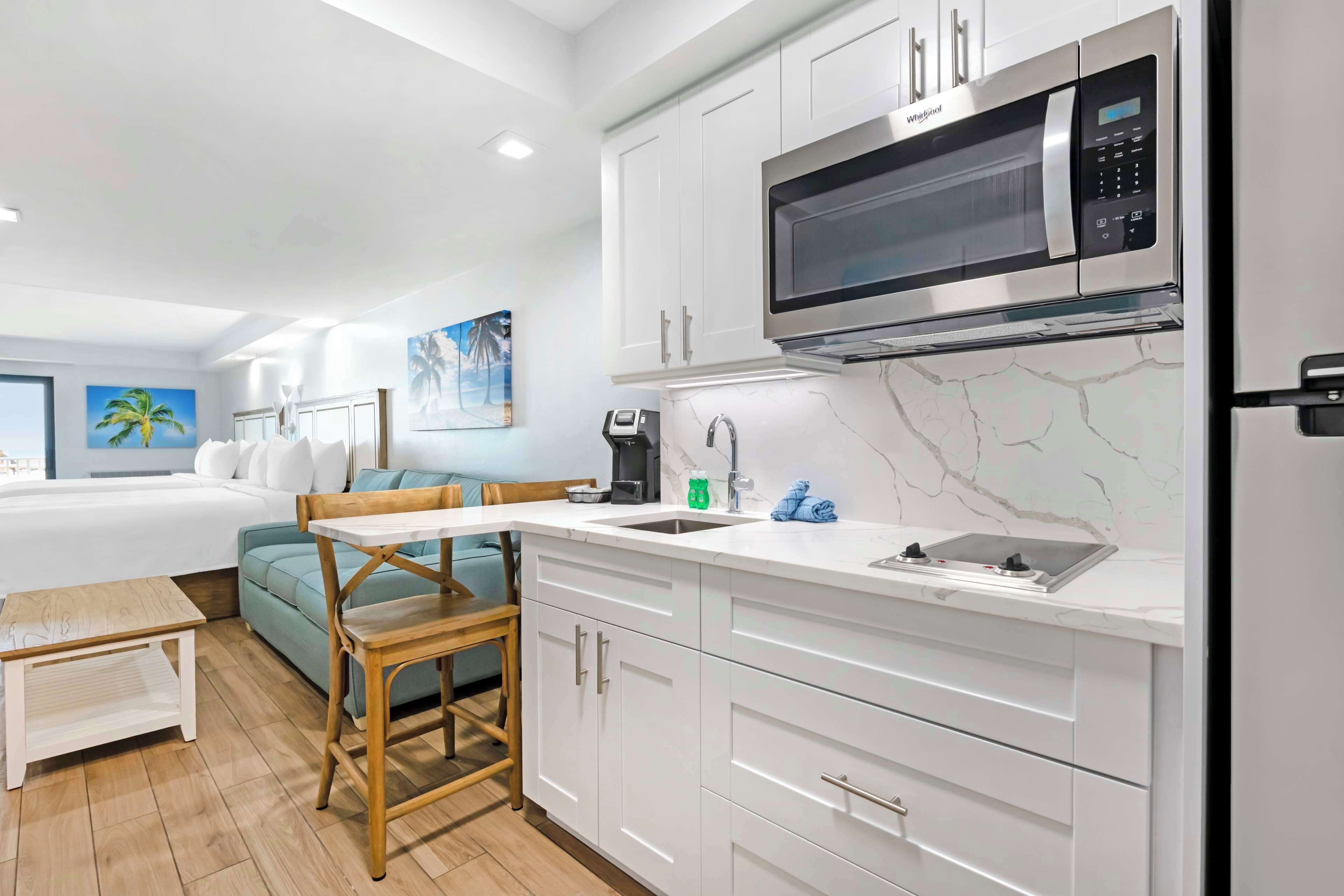 A modern kitchen with white cabinets, a built-in microwave, and a sink.
