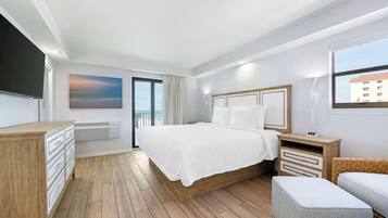 Et moderne hotelværelse med en stor seng, trægulv, et fjernsyn, et billede og udsigt ud.